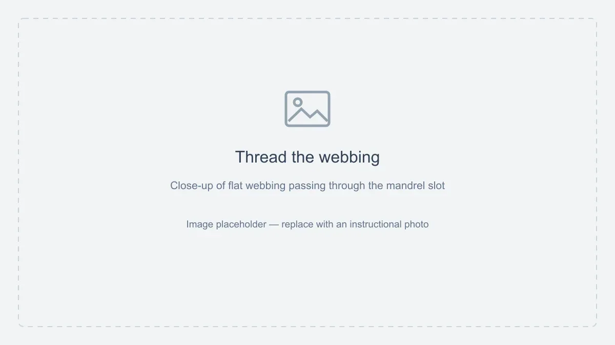 Image placeholder: Thread the webbing. Close-up of flat webbing passing through the mandrel slot.